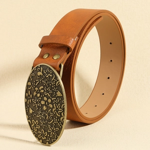 Close-up of brown leather belt with vintage floral engraved bronze metal buckle