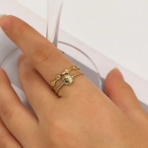 Detail of two gold stainless steel rings with sunburst and bead patterns on model hand