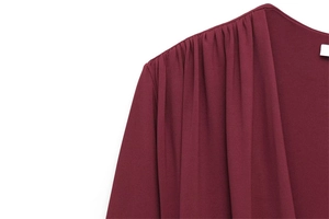 Detailed view of the pleated shoulder design on a burgundy wine red elegant dress