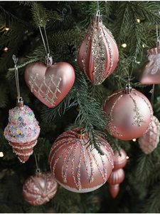 Pink heart and star ornaments showing glitter and matte textures on Christmas tree