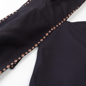 Detail of black dress featuring orange and white geometric diamond pattern embroidery