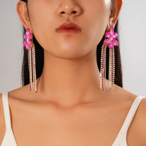 Boucles d'oreilles fleur à pompons avec strass roses et finition dorée sur modèle