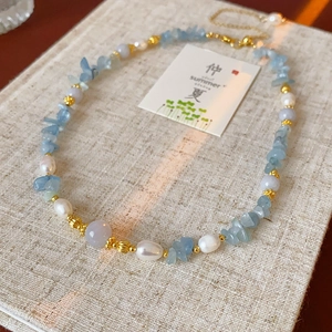 Détail du collier de plage avec pierres d'aigue-marine et perles sur tissu en lin