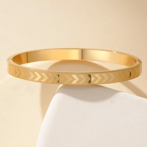 Gold titanium steel cuff bracelet with engraved arrow pattern on white stone base