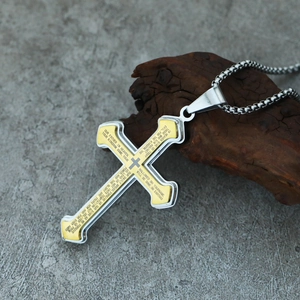 Macro shot of two-tone gold and silver cross pendant with Lord's Prayer engraving on wood