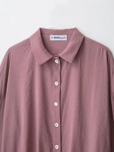 Detail of dusty rose long sleeve shirt with micro-wrinkle texture and white buttons