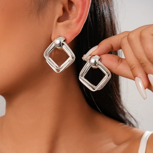 Boucles d'oreilles géométriques double losange en argent portées par un modèle