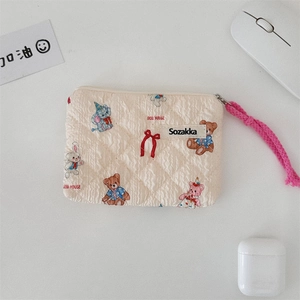 Detailed close-up of quilted floral cotton pouch with cartoon bear and pink rope zipper
