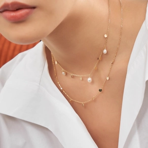 Close-up of double-layer gold necklace with freshwater pearls and metallic sequins