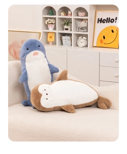 Plush seal and otter toys in grey and brown colors displayed on a cozy cream sofa