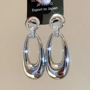 Close-up of silver-plated oval drop earrings with sparkling pavé-set cubic zirconia details