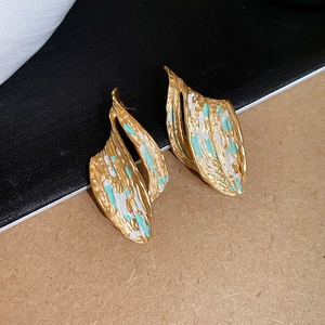 Detail showing irregular gold leaf earrings with white and turquoise painted texture