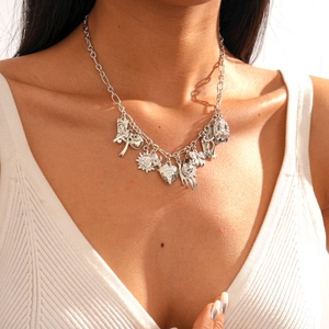 Detail of silver multi-pendant chain necklace featuring sun, heart, and hand charms