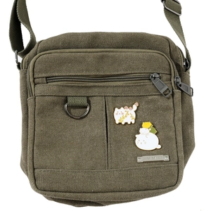 Détail de badges de chat et plaque de marque sur un sac bandoulière en toile verte
