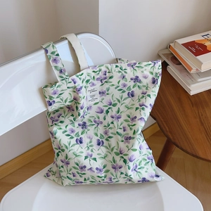 Dettaglio della borsa tote in tela a fiori blu e viola appesa a una sedia bianca
