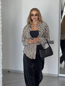 Dettaglio di una camicia con stampa geometrica bianca e nera e pantaloni larghi