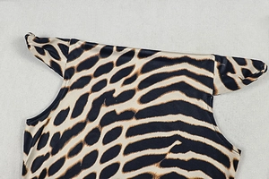 Close-up of leopard print mini dress neckline with sleek strap detail and polyester fabric