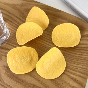 Macro detail of realistic artificial potato chip hair clips on a wooden tray
