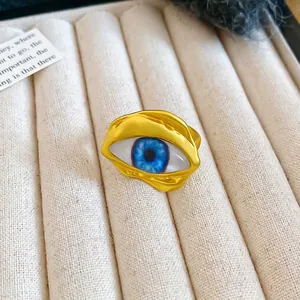 Unregelmäßiger goldener Evil Eye Ring mit blauer Pupille in einer Schmuckschatulle