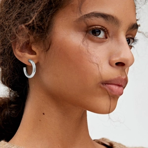 Close-up of chunky gold-plated C-shaped hoop earrings with a high-polished mirror finish