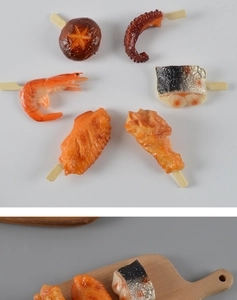 Detailopname van realistische PVC barbecuespiesjes met garnalen en kippenvleugels als decoratie