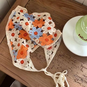 Detailed view of handmade crochet floral headscarf on a rustic wooden table setting