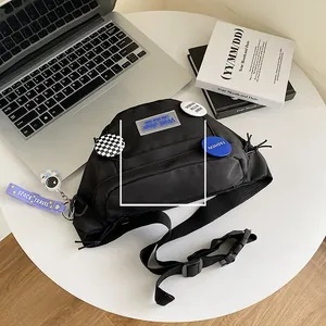 Close-up of black nylon chest bag with decorative badges and astronaut charm