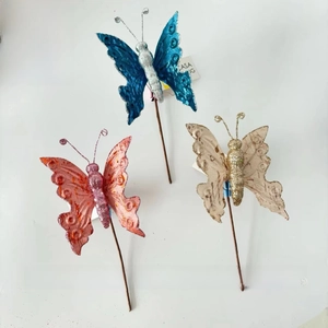 Detailed view of three velvet Christmas butterfly picks with glitter accents and stems
