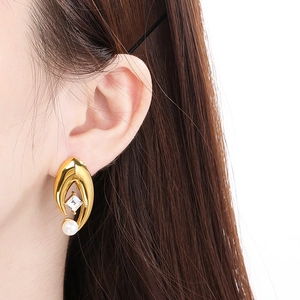 Gros plan de boucles d'oreilles en V dorées avec zircon carré et perle sur modèle