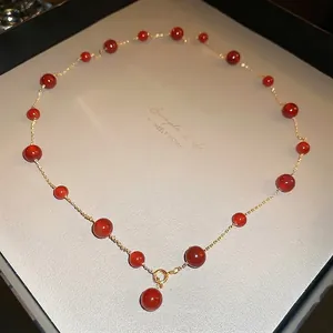 Elegant gold-plated red onyx bead necklace displayed on a minimalist jewelry tray