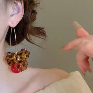 Detail of vintage leopard print flower earrings with red pearl bead on model