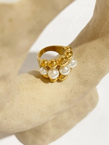 Macro shot of gold stainless steel multi-bead pearl ring on a beige display stand