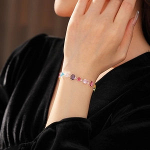 Close-up of a silver bracelet with multi-colored gemstones worn on a model's wrist