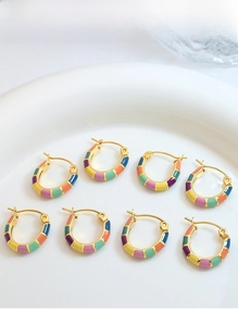 Détail de boucles d'oreilles créoles émaillées colorées dans un plat en céramique