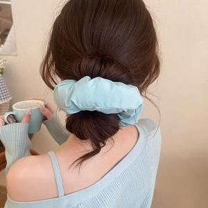 Close-up of a light blue oversized padded scrunchie worn on a bun for a soft elegant look