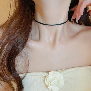 Close-up of a minimalist black faux leather choker necklace worn by a fashion model