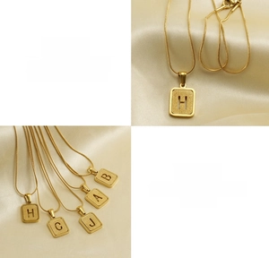 Detail of 18K gold titanium steel snake chain featuring hollow rectangle initial pendants