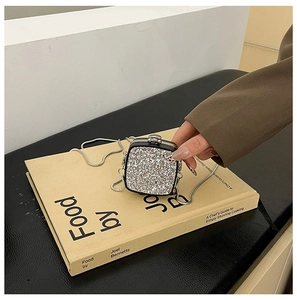 Close-up of silver sequin mini bag on a book showing the fine glitter and snake chain