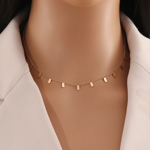 Close-up of golden stainless steel necklace with small rectangular charms on the clavicle