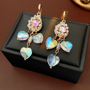 Macro shot of gold tassel earrings with iridescent crystals and pearls on black leather