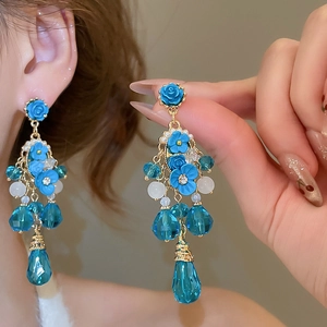 Détail macro de boucles d'oreilles fleurs bleues avec cristaux taillés et pétales en résine