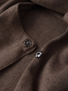 Macro shot of dark coffee knitted coat detail with metal snap buttons and ribbed texture