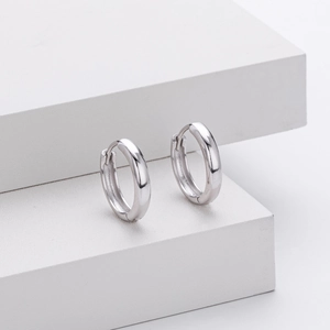 Macro detail of high-polished S925 sterling silver hoop earrings on white stand