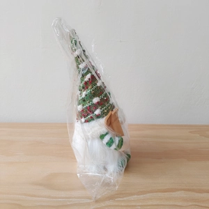 Close-up of Christmas gnome with knit hat and wooden skis on a wooden surface