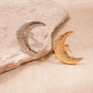 Detailed view of gold and silver moon rings with hammered metal texture on natural rock