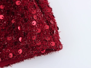 Dettaglio in primo piano del tessuto tweed rosso scuro con paillettes e lana