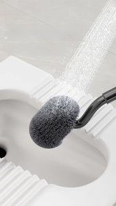 Detail of S-shaped toilet brush with grey bristles under running water for easy cleaning