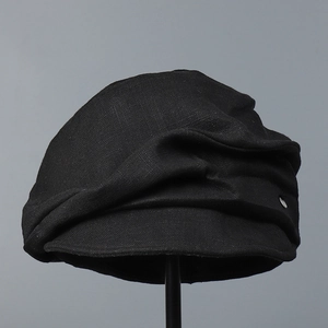 Detail of black cotton linen newsboy hat showing textured fabric and silver metal emblem