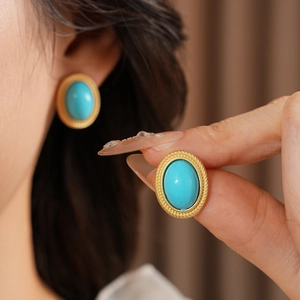 Close-up of vintage oval turquoise gemstone earrings with gold twisted rope texture