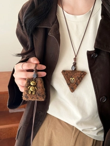 Detail of plush brown pendant necklaces featuring metal bear and triangle jeans charms